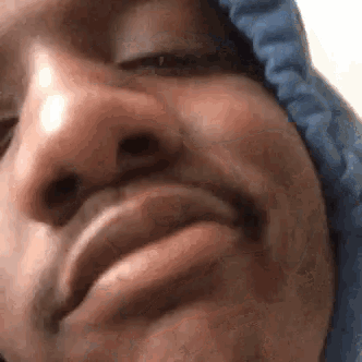 a close up of a man 's face with a blue hoodie on making a funny face .