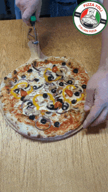 a pizza you italian pizza is being sliced on a wooden table