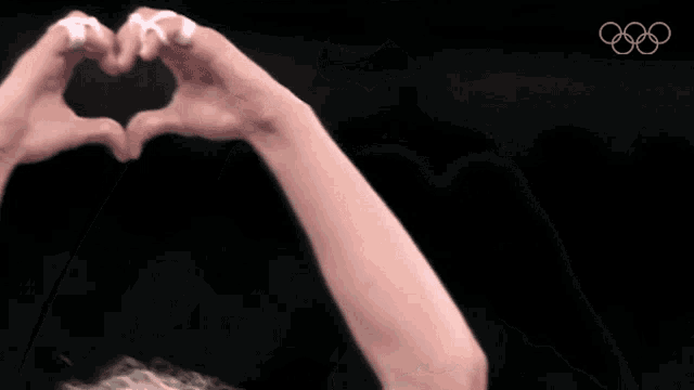 a person is making a heart shape with their hands