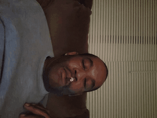 a man laying on a couch with his eyes closed and a piercing in his nose
