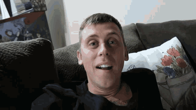 a man sitting on a couch with a floral pillow
