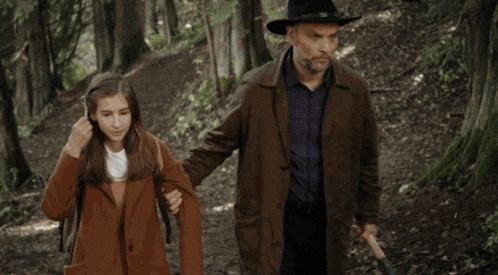 a young girl is walking through the woods with a backpack on her back .