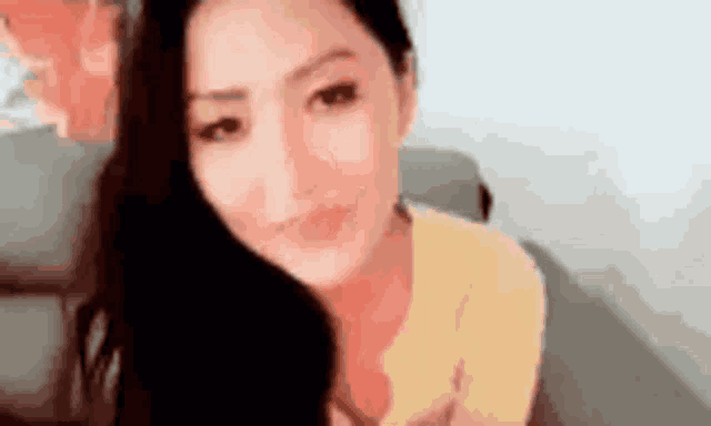 a woman in a yellow shirt is sitting on a couch .