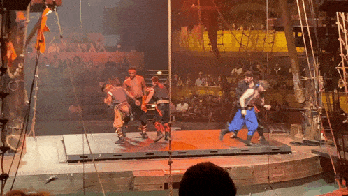 a group of men are dancing on a stage in front of a crowd of people
