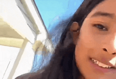 a close up of a girl 's face with long hair smiling and looking at the camera .