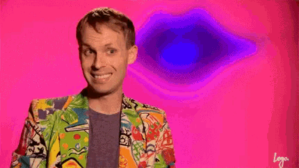 a man in a colorful jacket is smiling in front of a pink background with a purple eye .