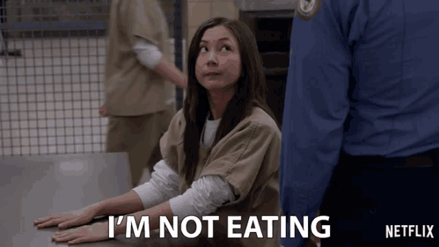 a woman is sitting at a table with the words i 'm not eating written on the bottom