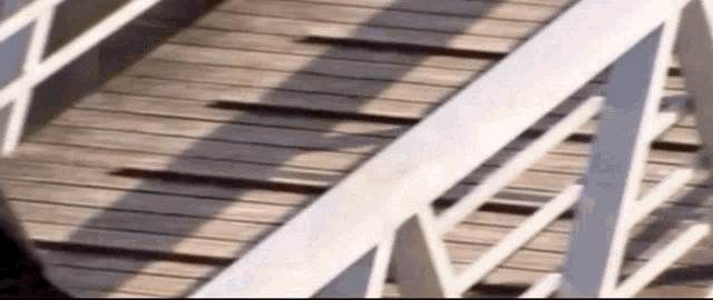 a white railing on a wooden deck with a shadow on it