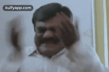 a man with a mustache is making a funny face while holding his head .