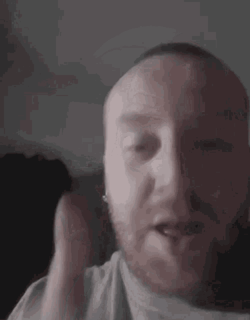a man with a beard is making a funny face while holding his hand to his face .