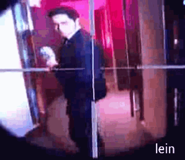 a man in a suit is standing in front of a mirror and the word lein is on the bottom
