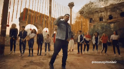 a man in a denim jacket is dancing in front of a group of children