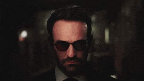 a man in a suit and tie is wearing red glasses and looking at the camera .