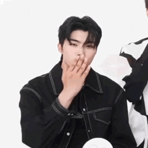 a young man is covering his mouth with his hand .