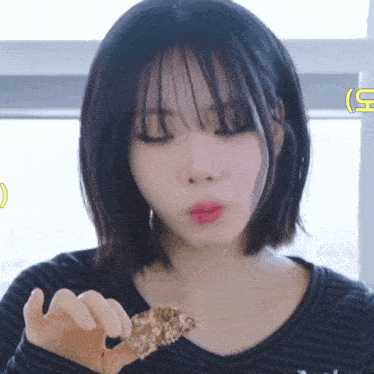 a woman eating a piece of food with a yellow g on the bottom