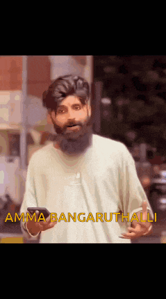 a man with a beard is holding a cell phone and says amma bangaruthalli