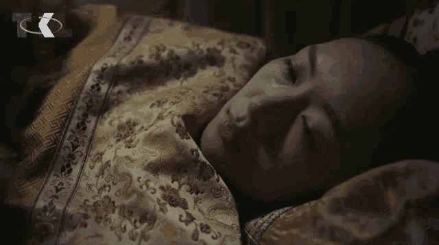 a woman is sleeping in a bed with a tk logo in the corner