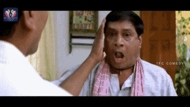 a man in a white shirt is being slapped by another man