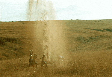 a group of people standing in a field with a geyser coming out of it