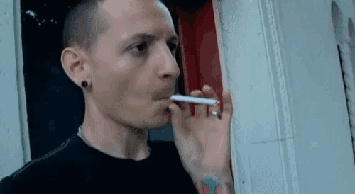 a man in a black shirt is smoking a cigarette .