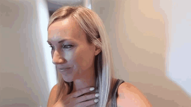 a woman is looking at herself in the mirror while touching her neck .