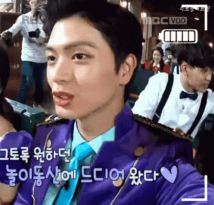 a young man wearing a purple jacket and tie is sitting in front of a mbc vod sign