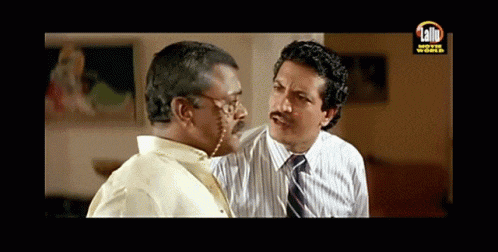 two men are having a conversation in front of a sign that says lalit movie world