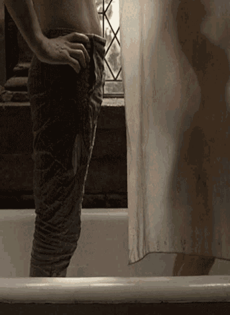 a person is standing in a bathtub with a shower curtain behind them
