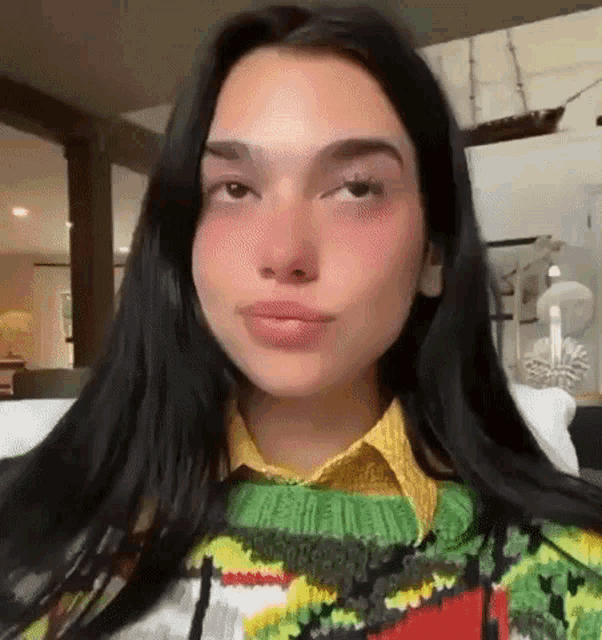 a close up of a woman 's face with a sweater on and a yellow shirt .
