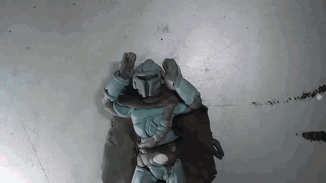 a clay figure of a knight is standing on a gray surface with his arms outstretched .