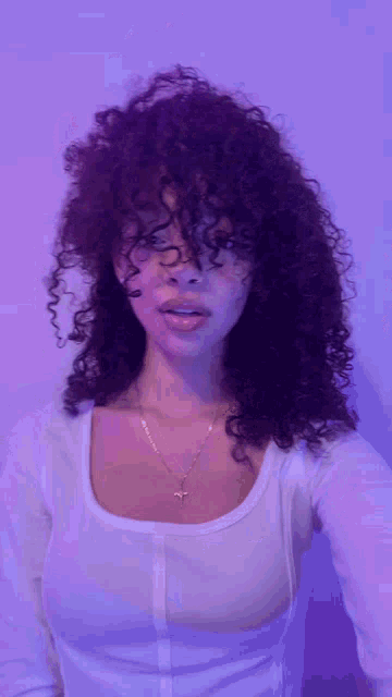 a woman with curly hair and a cross necklace
