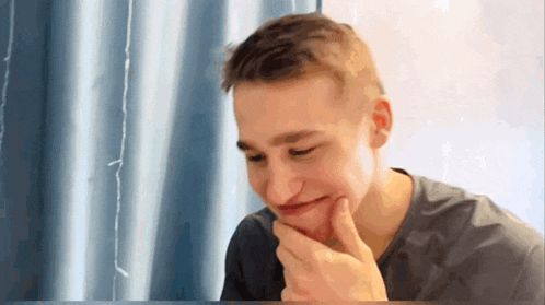 a young man is making a funny face with his hand to his chin .