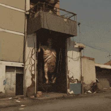 a statue of a man with a large belly is hanging from a balcony