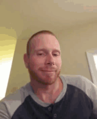 a man with a beard is smiling for the camera while wearing a blue shirt .