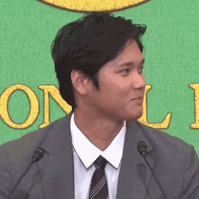 a man in a suit and tie stands in front of a sign that says on