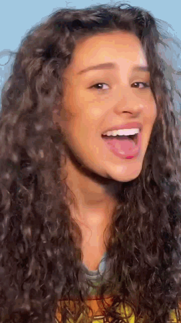 a close up of a woman with curly hair smiling with her tongue hanging out .