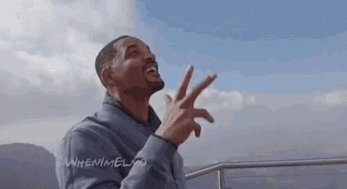 a man is standing on a balcony making a peace sign with his fingers .