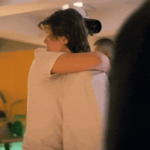 a man wearing a hat is hugging another man
