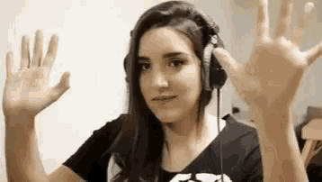 a woman wearing headphones is waving her hands in front of a wall .