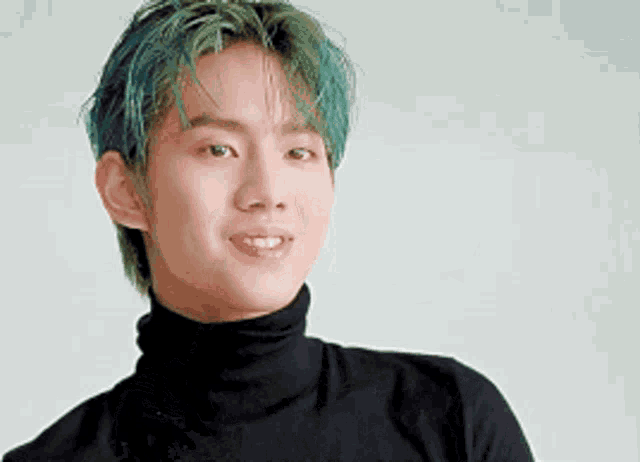 a young man with green hair and a black turtleneck is smiling .