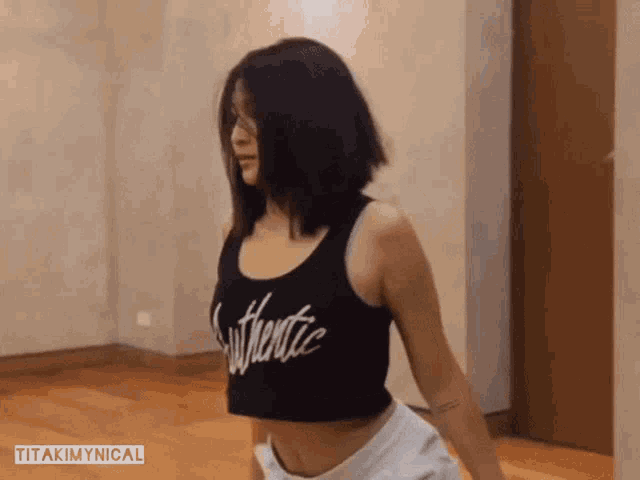 a woman in a black crop top and white shorts is dancing in a room .