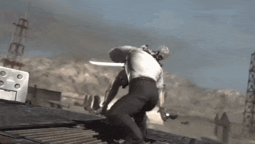 a man is holding a sword while standing on top of a roof .