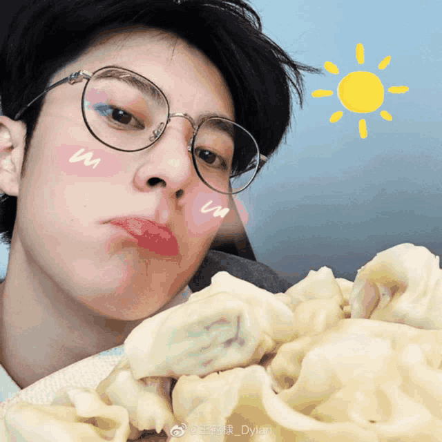 a young man wearing glasses is eating a plate of food with a sun behind him