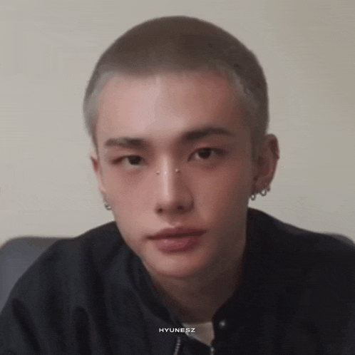 a close up of a young man with a shaved head and earrings .