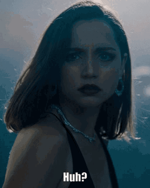a woman in a black dress is looking at the camera with the words huh below her