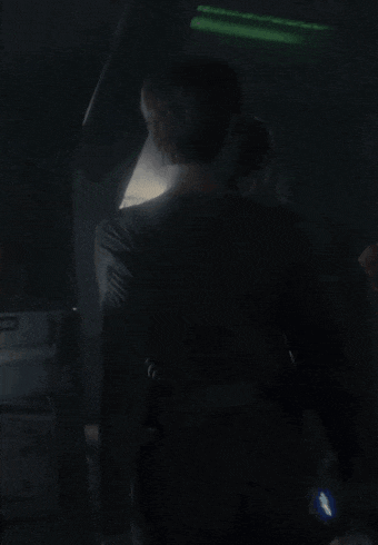 a couple of people standing in a dark room with a green light behind them