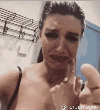 a woman is crying and making a funny face while holding her finger to her face .