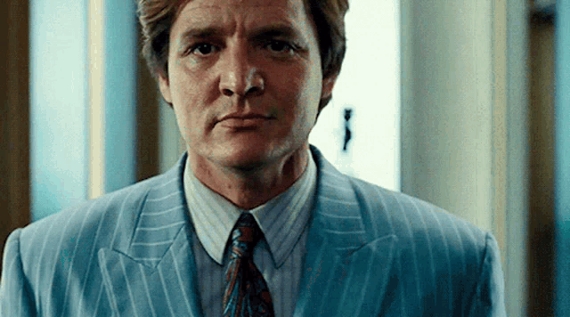 a man in a suit and tie is standing in a room .