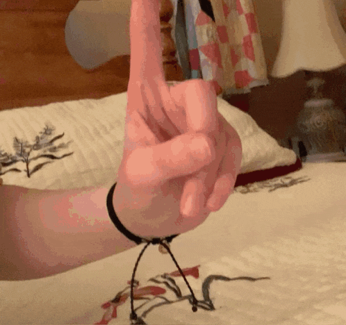 a person 's hand with a bracelet on their wrist is making a peace sign