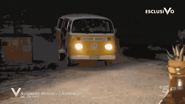 a yellow van is driving down a dirt road in the dark